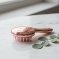 Rose gold scalp massager shampoo brush on marble surface with eucalyptus leaves