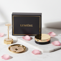 Under eye gel patches in elegant black packaging on white marble surface with gold accents and rose petals